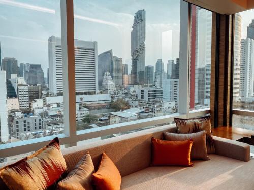 a couch in a room with a large window at Le Meridien Bangkok in Bangkok