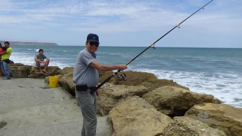 a man holding a fishing pole on the beach at Hostal Rosa Mar in Manta