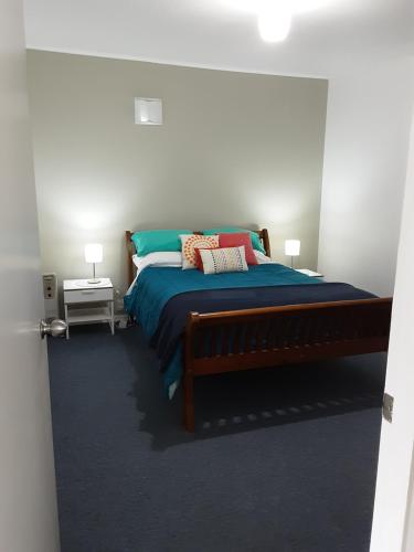 1 dormitorio con 1 cama con sábanas y almohadas azules en Relax@99 en Featherston