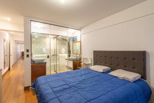 a bedroom with a blue bed and a bathroom at Corpac Apartment in Lima