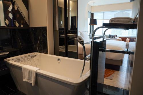 a bathroom with a bath tub next to a bedroom at Le Meridien Bangkok in Bangkok