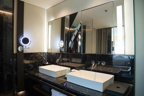 a bathroom with two sinks and a large mirror at Le Meridien Bangkok in Bangkok