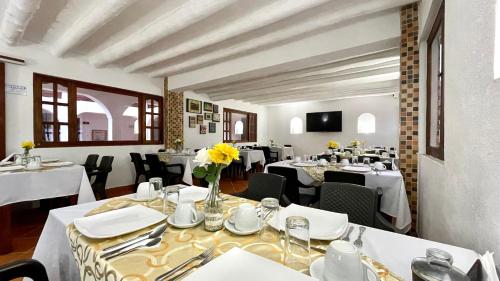 a restaurant with white tables and chairs with yellow flowers at Hotel Boutique & Spa - VDL Colonial in Villa de Leyva