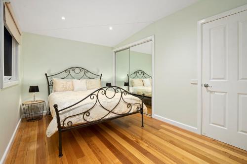 a bedroom with a bed and a mirror at Paddys Creek Retreat in Upwey
