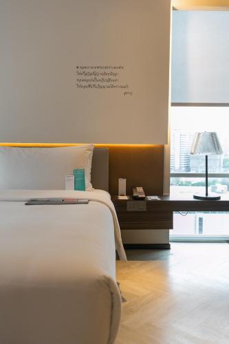 a bedroom with a bed and a desk and a window at Le Meridien Bangkok in Bangkok