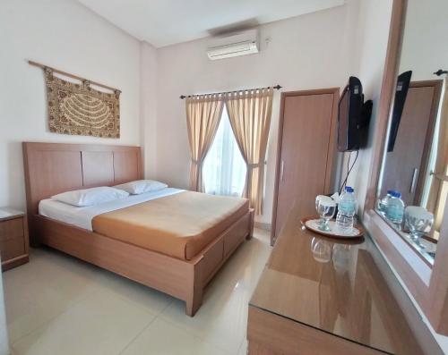 a bedroom with a bed and a flat screen tv at The Sriwijaya Hotel - Halal Hotel in Padang