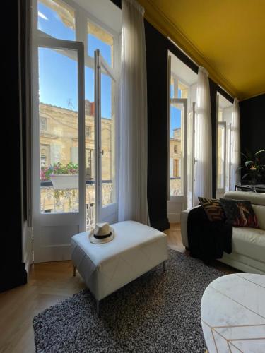 a living room with a white ottoman and large windows at The Suites in Blaye