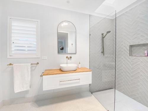 ein weißes Bad mit einem Waschbecken und einer Dusche in der Unterkunft Lusso Retreats in Moffatdale