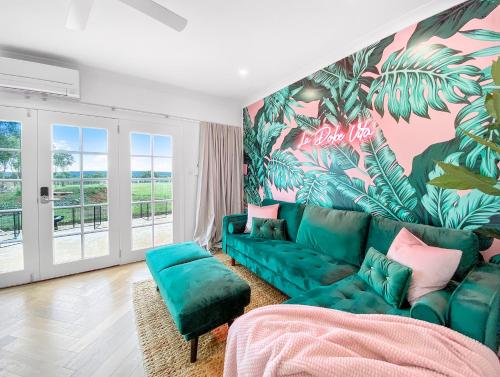 ein Wohnzimmer mit einem grünen Sofa und einer tropischen Wand in der Unterkunft Lusso Retreats in Moffatdale