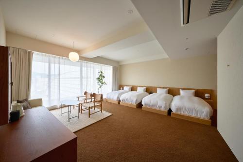 a bedroom with four beds and a table and chairs at Hotel Lepo Chahal in Matsuyama