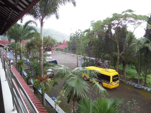 a yellow bus parked in a parking lot with palm trees at Sukapura Permai Hotel in Lambangkuning