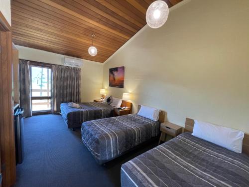 a hotel room with two beds and a window at Mountain Creek Motel Bar & Restaurant in Mount Beauty