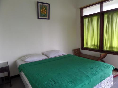 a bedroom with a green bed and a window at Sukapura Permai Hotel in Lambangkuning