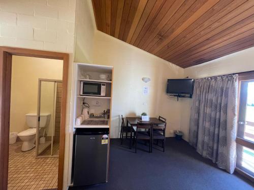 a room with a kitchen and a table with a microwave at Mountain Creek Motel Bar & Restaurant in Mount Beauty