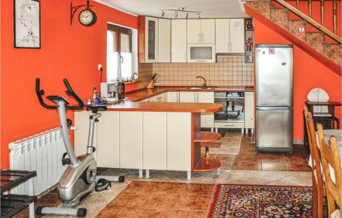 a kitchen with orange walls and a treadmill at Gorgeous Home In Ruciane-nida With Sauna in Ukta