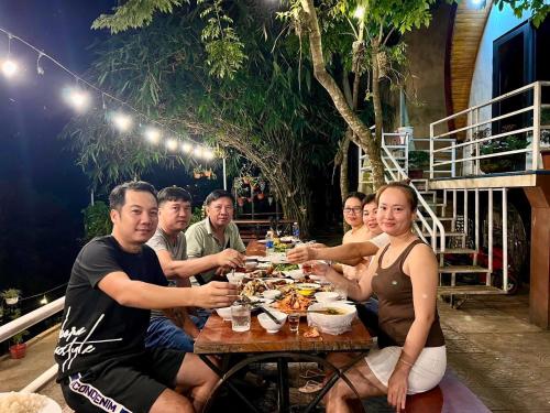 a group of people sitting at a table eating food at Areca Bungalow in Phong Nha