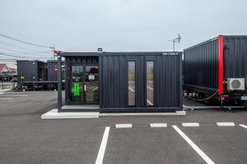 un pequeño edificio negro en un estacionamiento en HOTEL R9 The Yard Uki en Uki