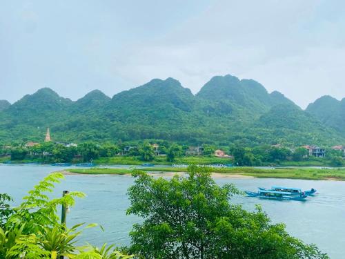 two boats on a river with mountains in the background at Areca Bungalow in Phong Nha