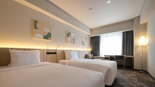 a hotel room with two beds and a desk at ANA Holiday Inn Sendai by IHG in Sendai