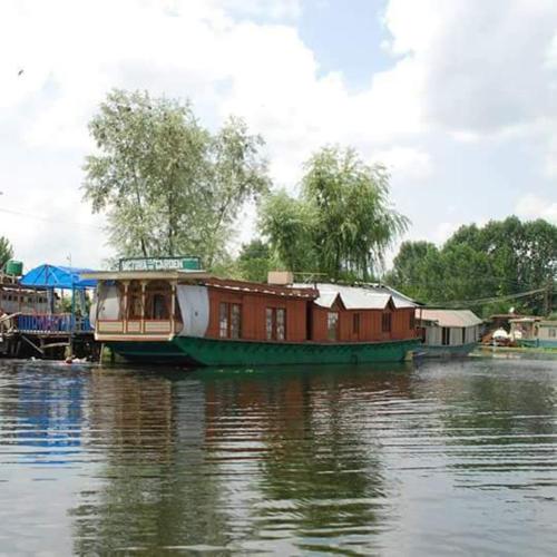 a house boat sitting on the water next to a dock at H.B.victoria Garden in Srinagar