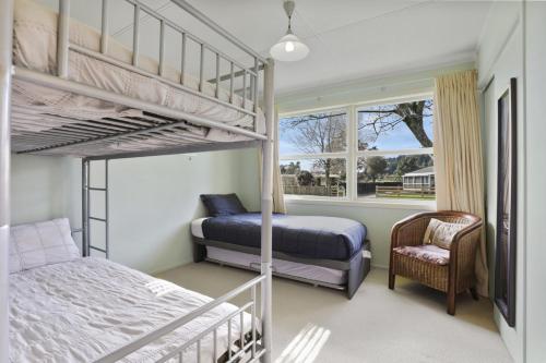 a bedroom with two bunk beds and a chair at Pukeko Lodge - Tūrangi Holiday Home in Turangi