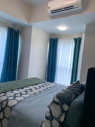 Schlafzimmer mit einem Bett mit blauen Vorhängen und einem Ventilator in der Unterkunft Le Maisse Executive Studio 1BR opp Okada in Manila