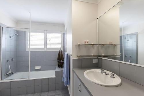 La salle de bains est pourvue d'un lavabo, d'une baignoire et d'un miroir. dans l'établissement 12 60 Peregian Esplanade Peregian Beach, à Peregian Beach