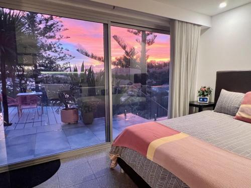 1 dormitorio con 1 cama y una gran ventana de cristal en Scandi Beach apartment en Avalon