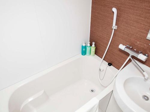 a bathroom with a white tub and a sink at Hotel Route Inn Matsuyama -Katsuyama Dori- in Matsuyama