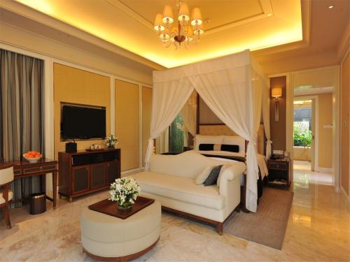 a bedroom with a white bed and a television at Wanda Reign Resort & Villas Sanya Haitang Bay in Sanya