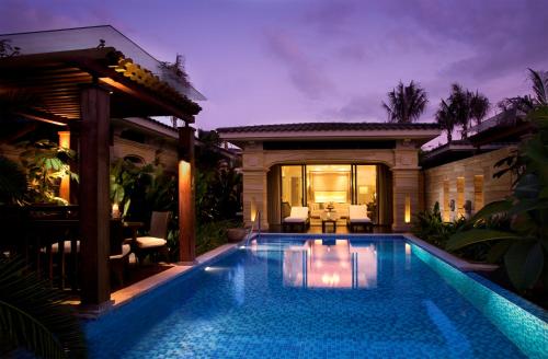 a swimming pool in front of a house at Wanda Reign Resort & Villas Sanya Haitang Bay in Sanya