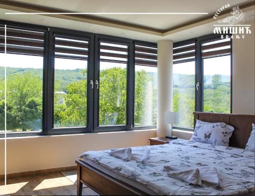 a bedroom with a bed and large windows at Zoo Misic Prenoćište in Vranje