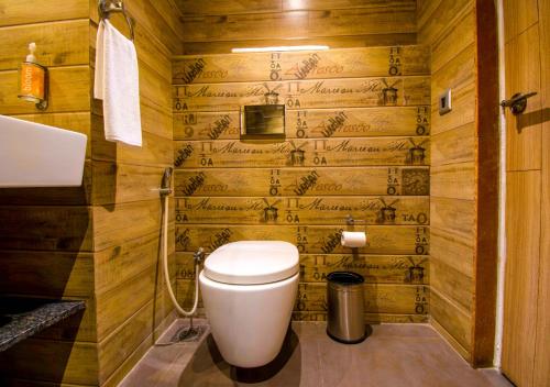 a bathroom with a toilet and wooden walls at Bloom Hotel - Gachibowli in Hyderabad