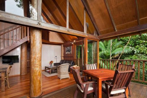 a room with a wooden table and chairs on a deck at Rose Gums Wilderness Retreat in Butchers Creek