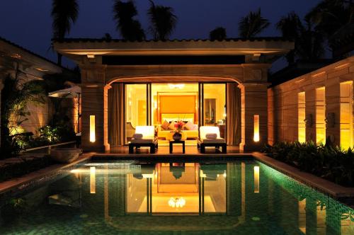 a swimming pool with two chairs and a couch at Wanda Reign Resort & Villas Sanya Haitang Bay in Sanya
