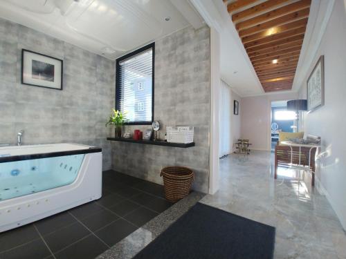 a large bathroom with a tub and a table at Oh Happy Day Jeju in Jeju