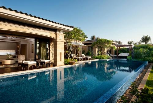 a swimming pool in front of a house at Wanda Reign Resort & Villas Sanya Haitang Bay in Sanya
