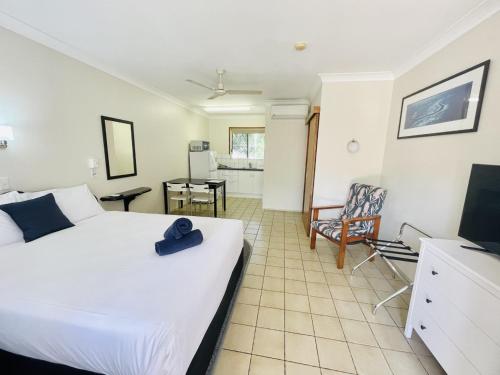 a bedroom with a large white bed and a chair at Paradise Court Holiday Units in Airlie Beach