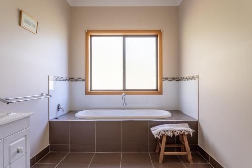 a bath tub in a bathroom with a window at Norfolk Bay Retreat - views over the sea and vines 