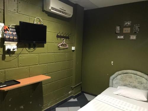 a room with a green wall with a bed and a desk at MOTEL TERMINAL INN in Inanam