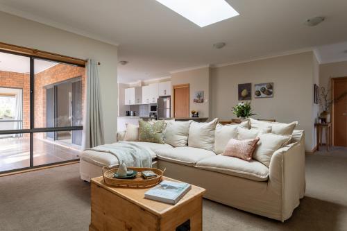 a living room with a couch and a table at Norfolk Bay Retreat - views over the sea and vines in Koonya