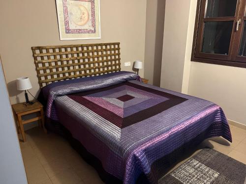 um quarto com uma cama com um edredão roxo em Apartamento a pie de pistas de Espot ZZ House em Espot