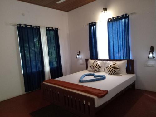 a bedroom with a bed with blue drapes at Loveshore Marari in Mararikulam