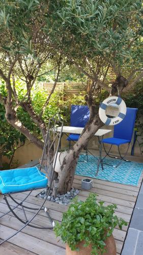 a table and chairs on a deck under a tree at Les terrasses des Anthenors in La Redonne