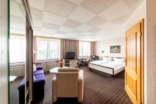 ein Hotelzimmer mit einem Bett und einem Sofa in der Unterkunft Hotel Forstmeister in Schönheide