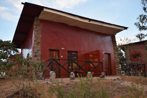 a red house with a red wall at Ngari Hill EcoLodge, Maralal - Kenya in Maralal
