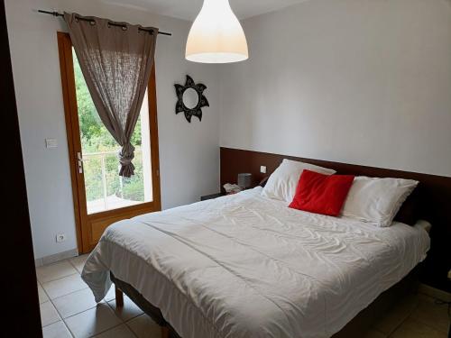 Villa de la croix de la main في Veyrignac: غرفة نوم بسرير ومخدة حمراء ونافذة