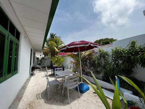 eine Terrasse mit einem Tisch, Stühlen und einem Sonnenschirm in der Unterkunft Gaskara Guesthouse in Shaviyani Atoll