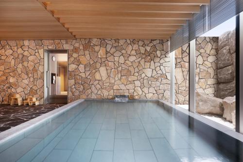 a swimming pool in a house with a stone wall at Setsu Niseko in Niseko