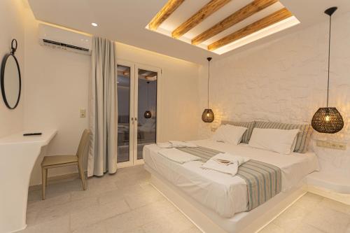 a white bedroom with a bed and a desk at Kallithea Hotel in Agia Anna Naxos